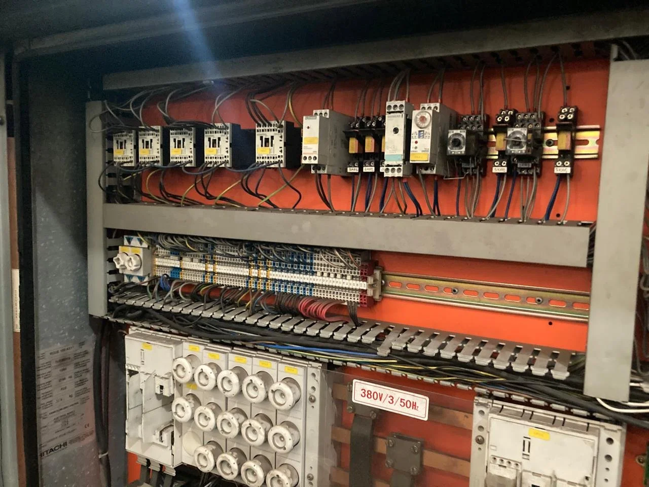 Panel de control eléctrico con componentes y cables, incluyendo contactos, relés y disyuntores, con etiqueta que indica 380V/3/50Hz.