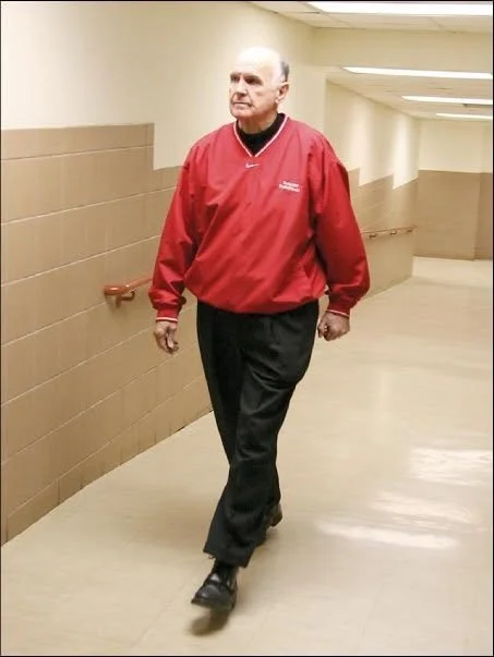 Hall of Fame basketball coach Lewis Orr walking purposely through a hallway at Navarro College in Corsicana, Texas.