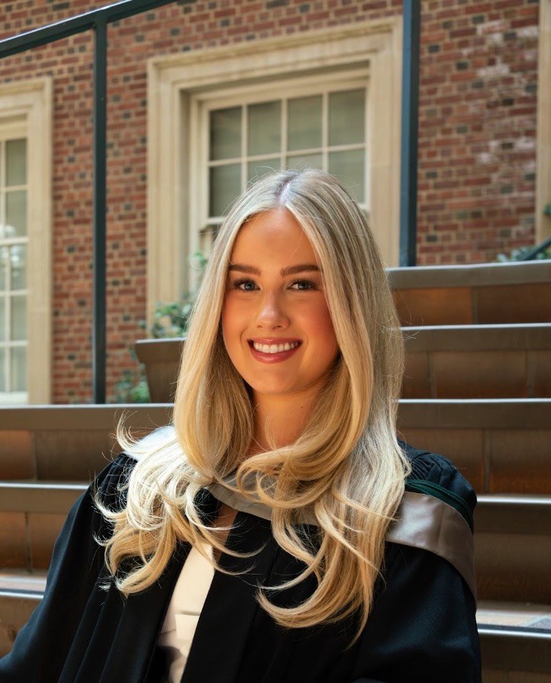 Blonde young woman in a graduation robe, smiling