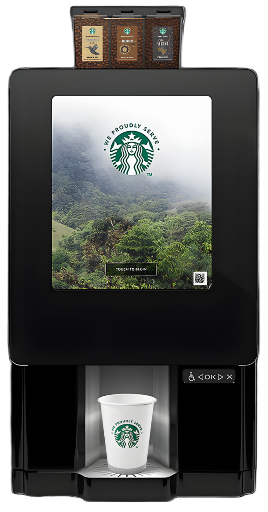 A Starbucks coffee vending machine with a digital screen displaying a scenic forest landscape and the Starbucks logo. The machine dispenses coffee into a white cup with the Starbucks logo placed on the drip tray.
