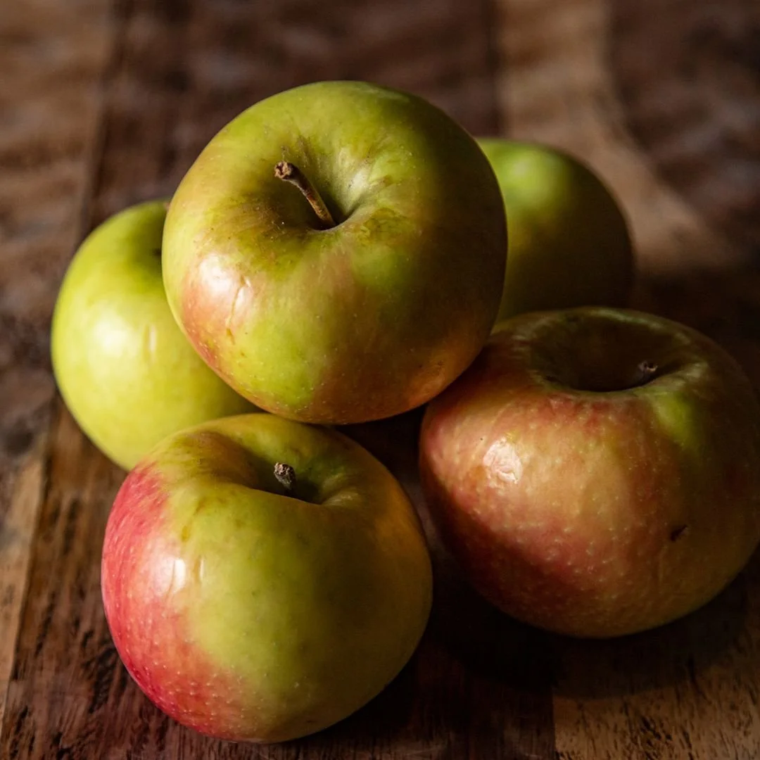 Five apples on a wooden surface, with three being green and two showing a mix of red and green.