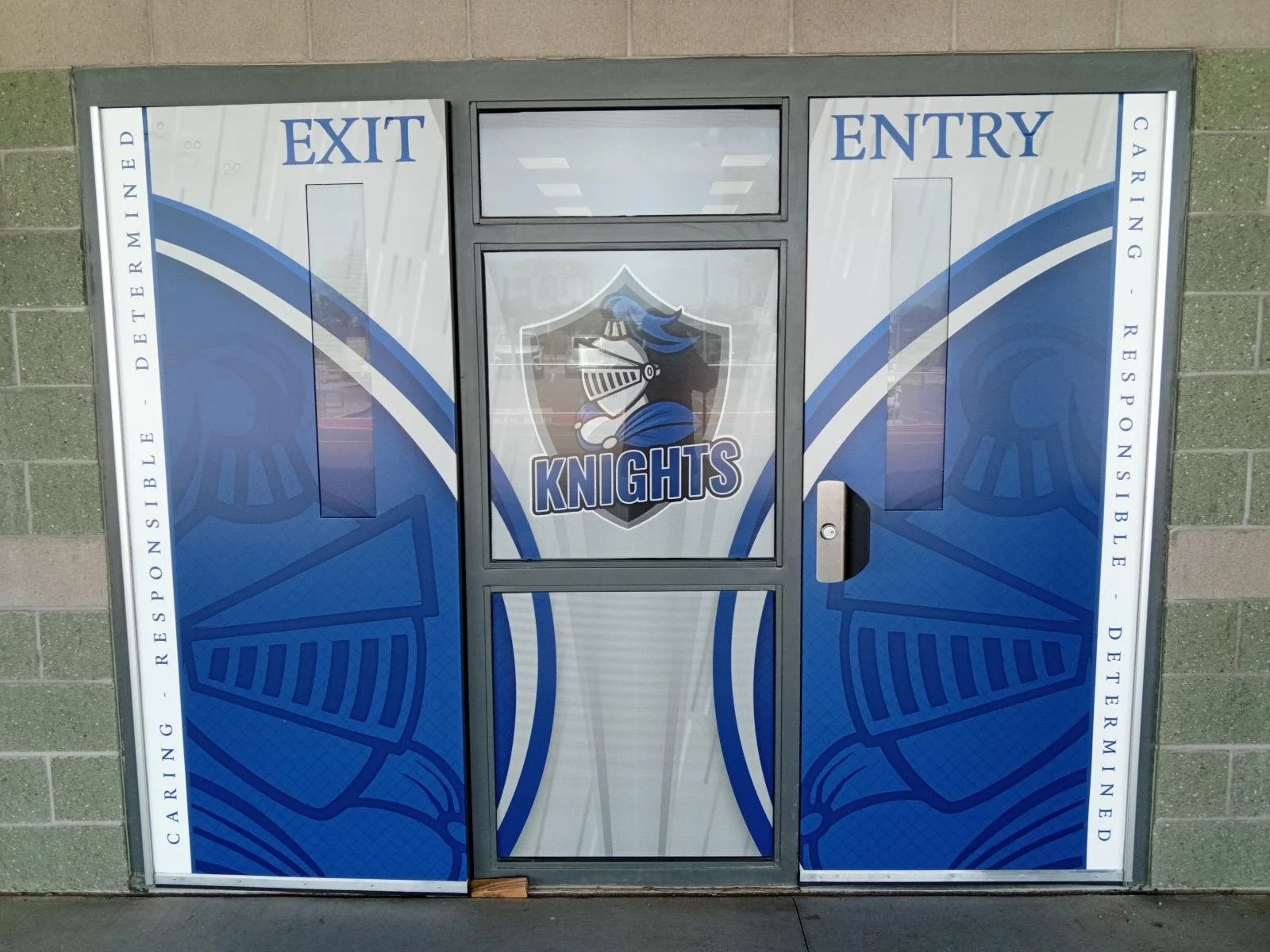 Double door with hockey-themed graphic, the words 'EXIT' on the left side and 'ENTRY' on the right side, a central logo of a knight's helmet with a blue plume and the word 'KNIGHTS' underneath.