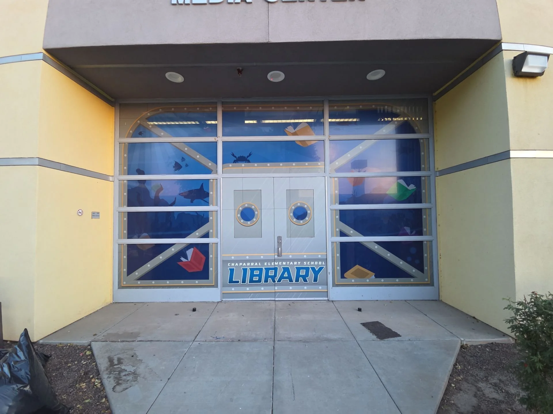 Entrance to Chaparral Elementary School with a large window decorated with underwater sea creatures and books, and a sign that reads "LIBRARY."