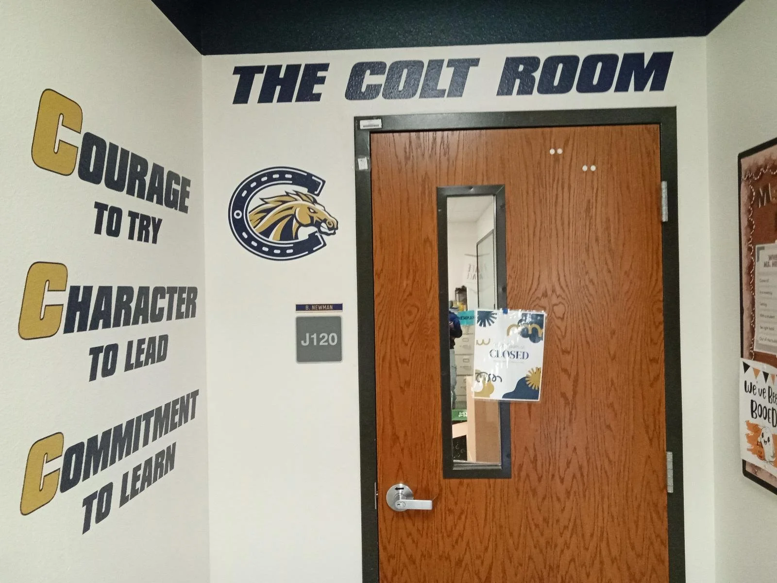 Door to 'The Colt Room' with a 'Closed' sign, surrounded by motivational quotes on the wall, including 'Courage to try,' 'Character to lead,' and 'Commitment to learn.'