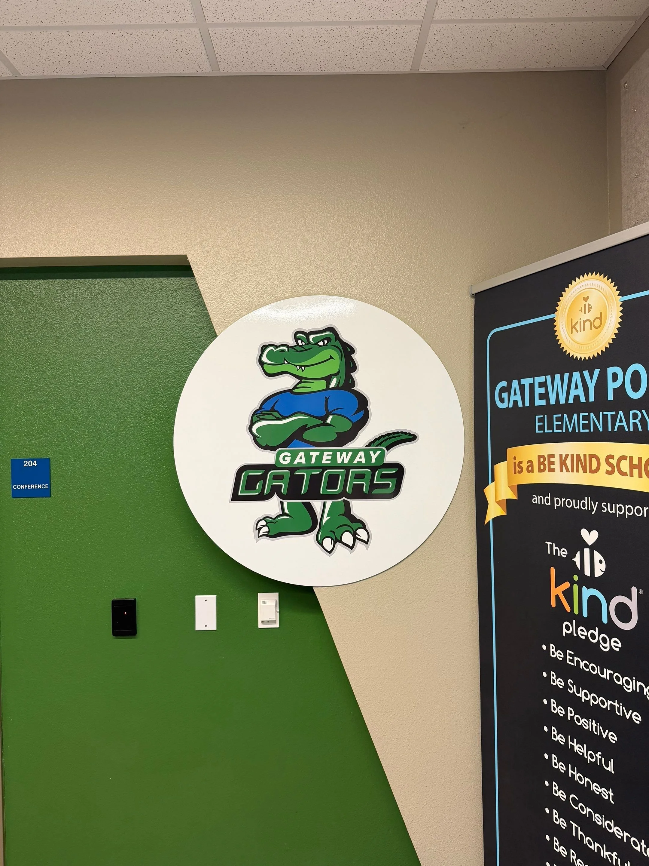 The image features a sign with a cartoon alligator mascot and the words 'Gateway Gators,' along with a banner promoting a 'Be Kind' pledge for an elementary school.