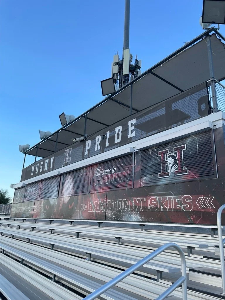 Empty football stadium stands with a banner displaying the words "HUSKY PRIDE," the University of Idaho logo, and messages welcoming visitors to Idaho and Hamilton Huskies.