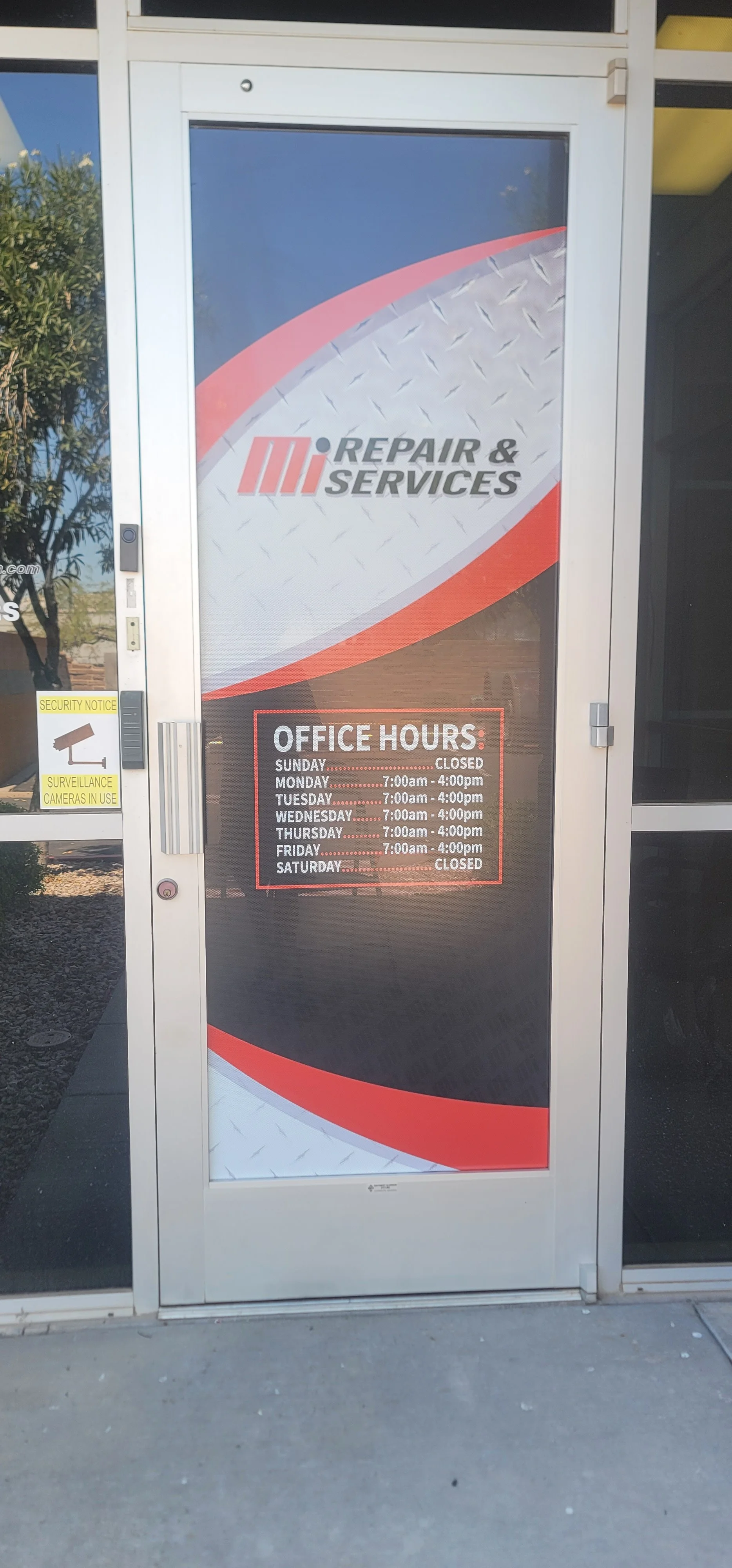 Sign on a door for a repair and services business, displaying office hours and a logo with red, black, and gray colors.