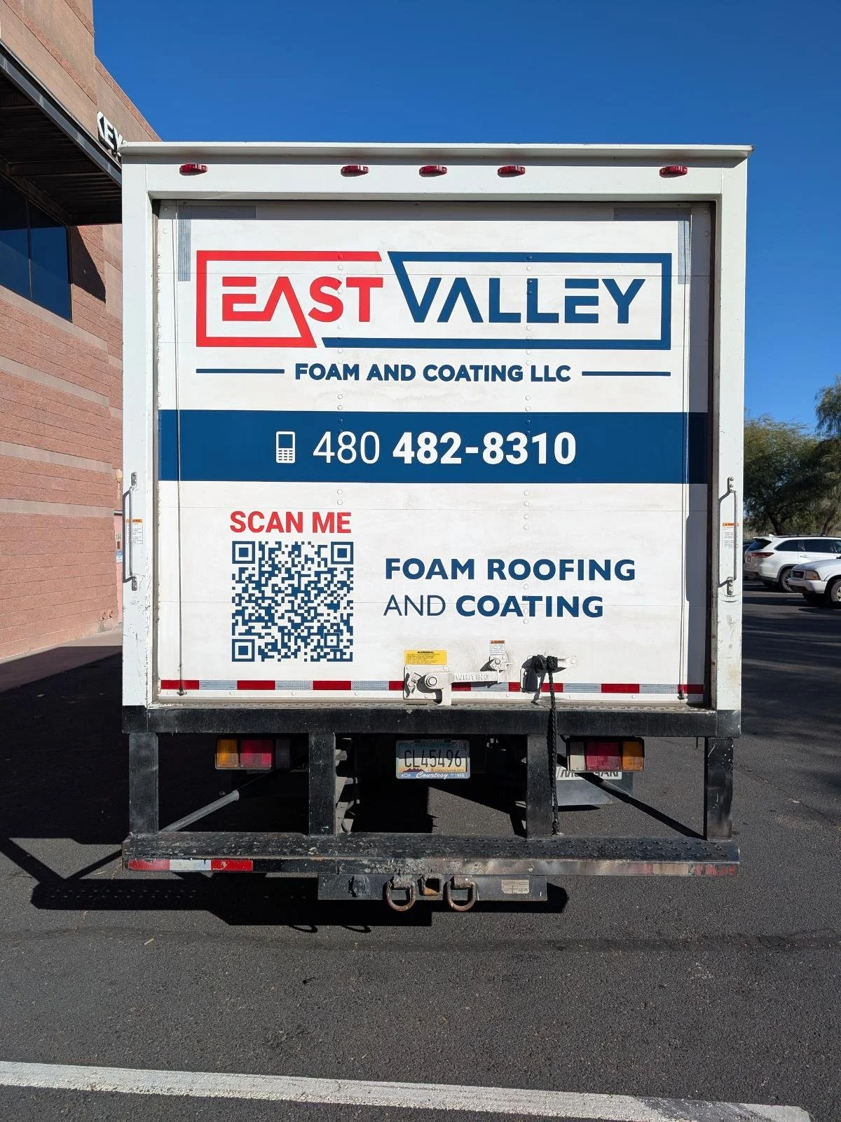 A truck advertising East Valley Foam and Coating LLC offers foam roofing and coating services. The sign includes a phone number, a QR code to scan, and mentions foam roofing and coating with a blue and red color scheme.