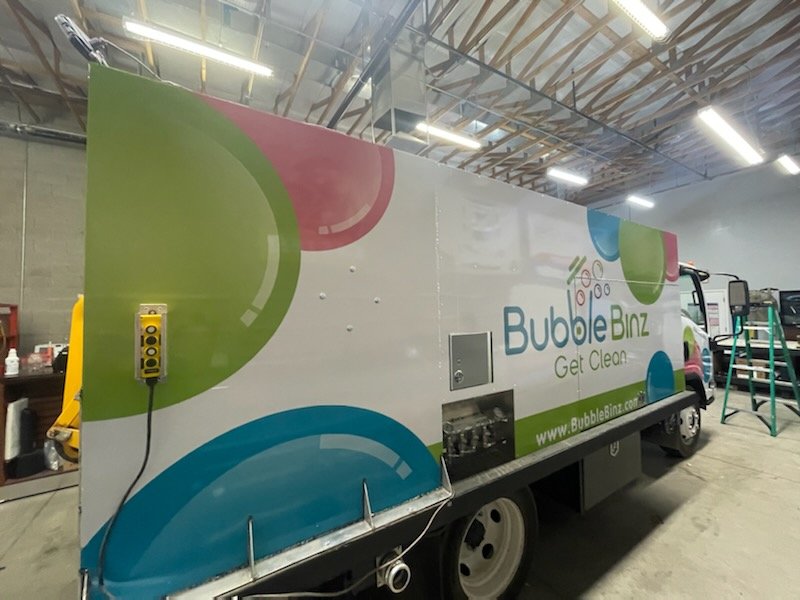 A mobile cleaning service truck with colorful bubble graphics and the text 'Bubble Binz' along with the slogan 'Get Clean' and a website URL.