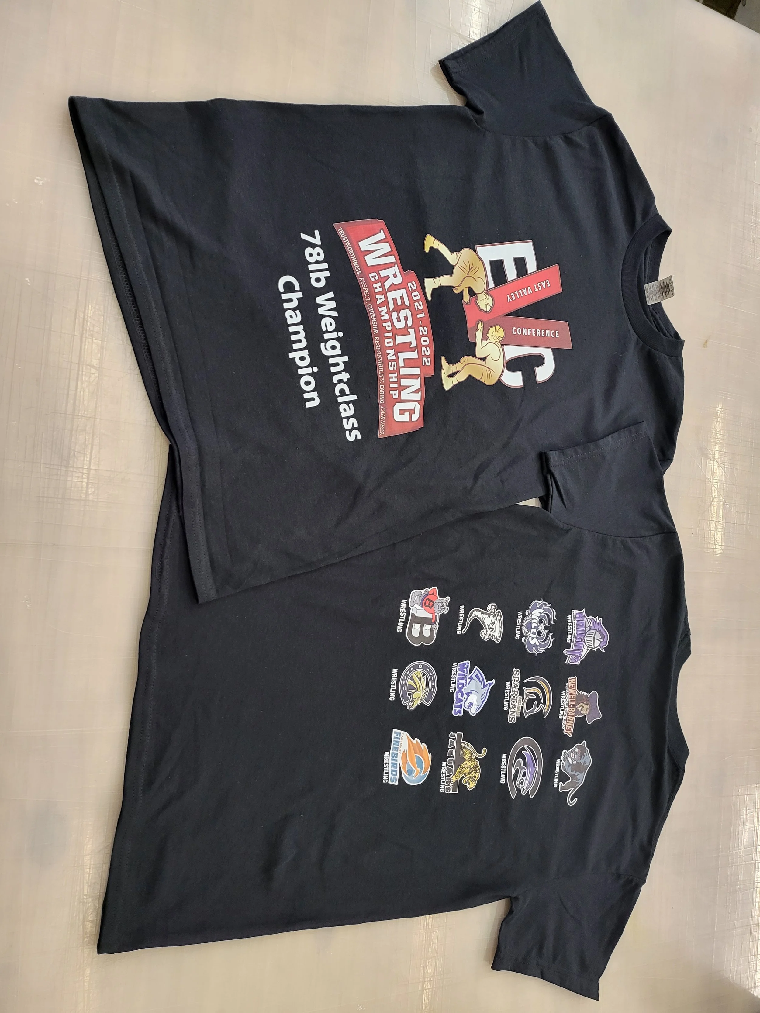 Black T-shirt with gymnastics event logos and sponsor details, commemorating the 2021-2022 season and the 141st Weightlifting Championship.