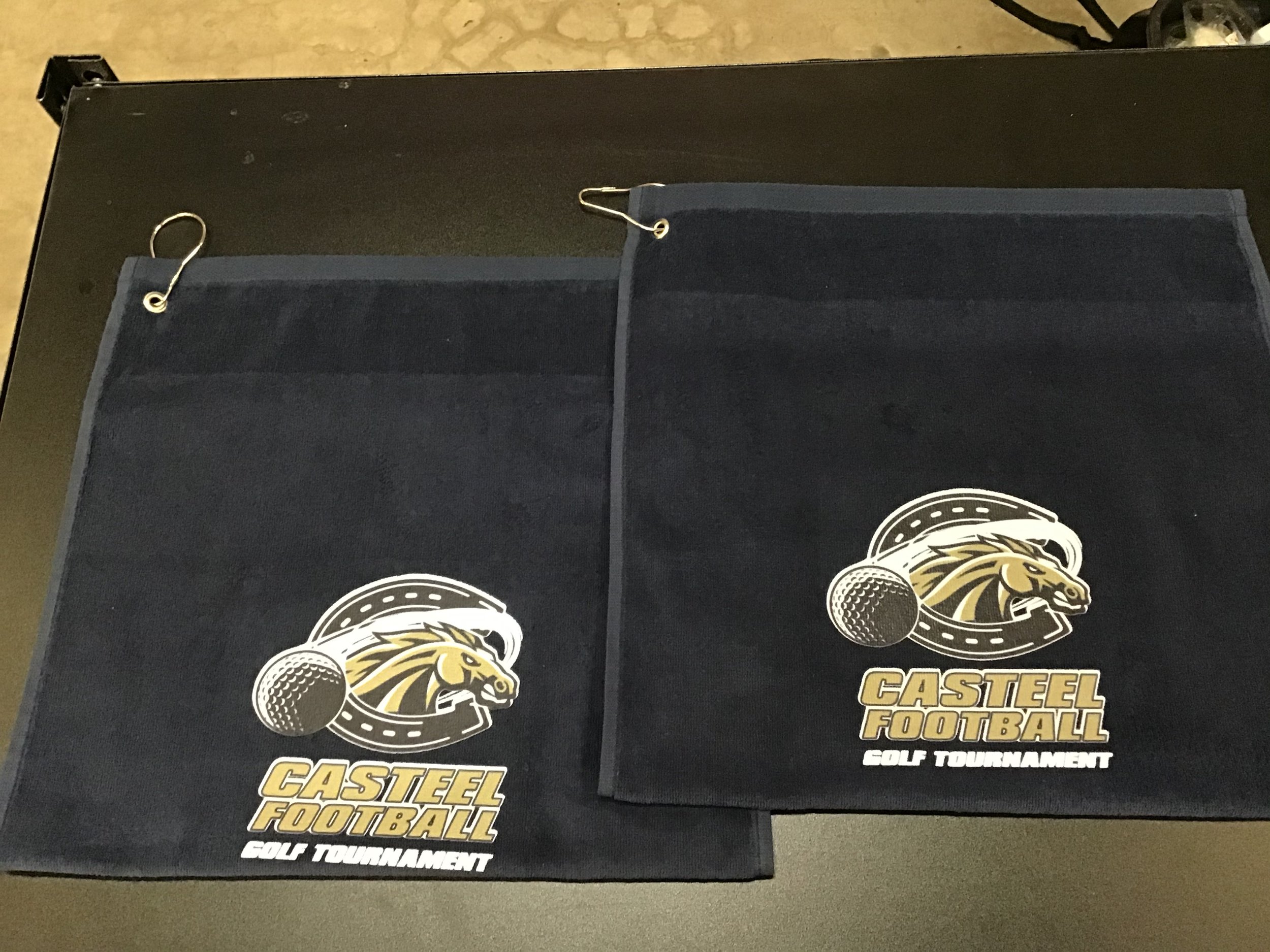 Two black boxes with the logo and text for the Castle Steel Football Golf Tournament, showing a lion's head with a microphone and golf ball.