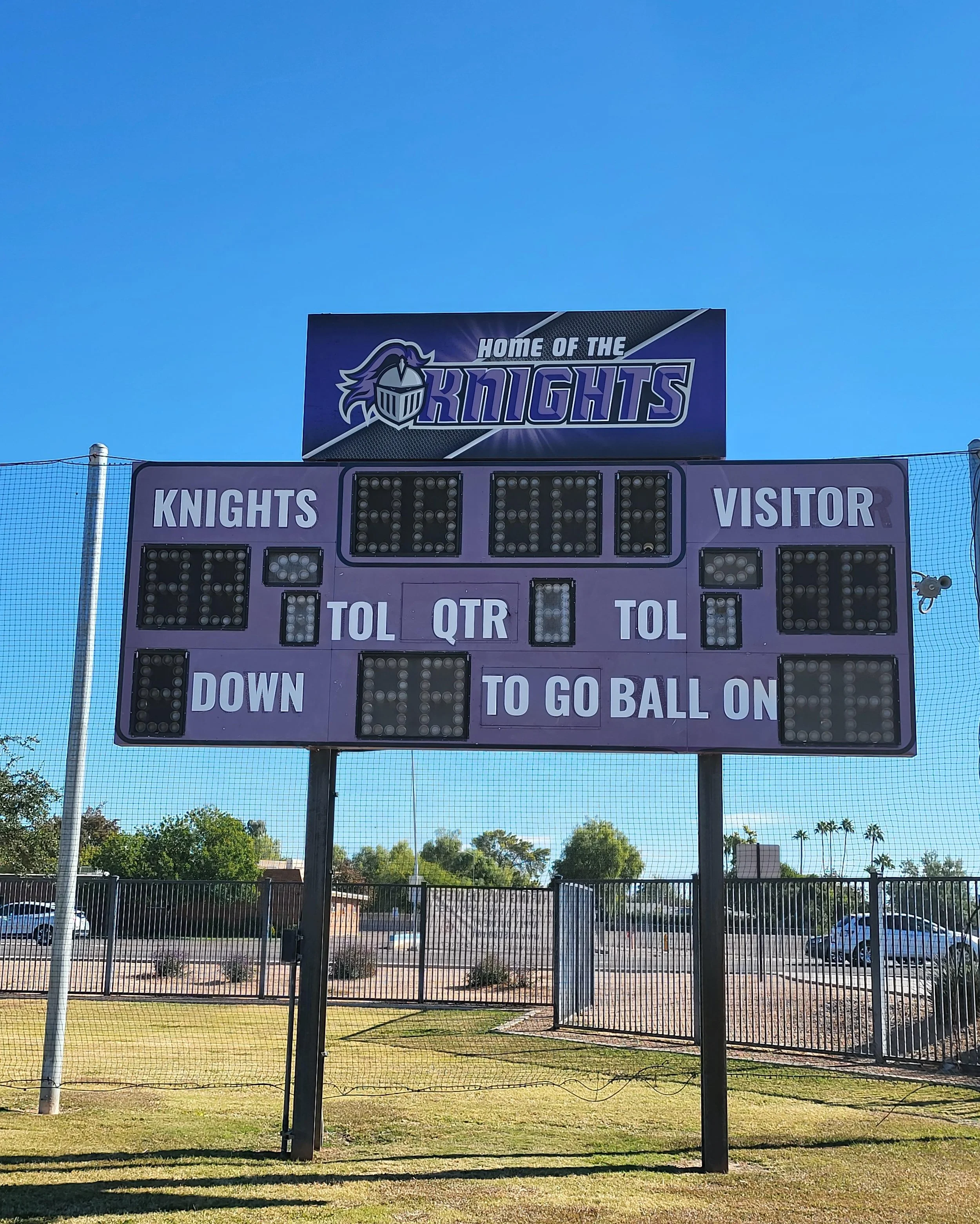 A sports scoreboard at a school field with the school's logo and name 'Knights' displayed at the top, and the words 'Home of the Knights'.