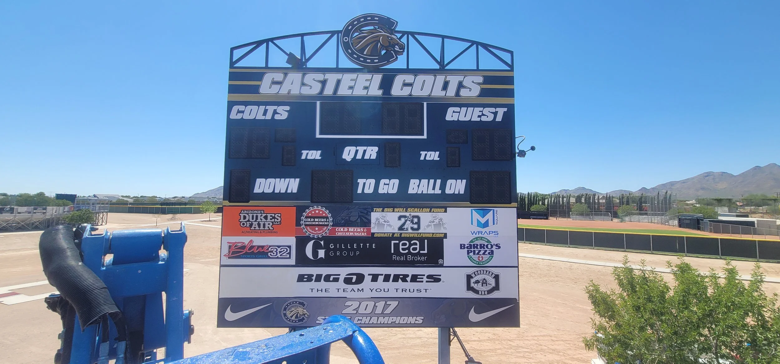 A baseball scoreboard at a sports field, with no scores displayed. The top shows the team name 'Castel Colts' and a mascot logo of a horse, with sections for team scores, guest team scores, and game details. The bottom features multiple sponsor logos