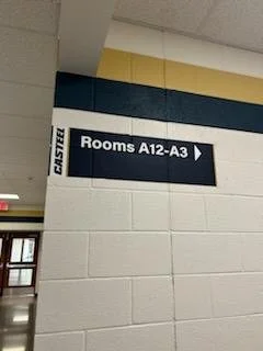 Sign indicating rooms A12 to A3 in a hallway