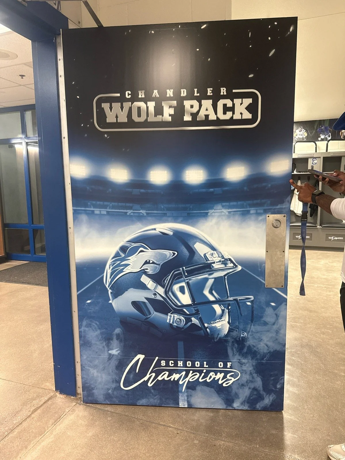 Poster promoting Chandler Wolf Pack, a school football team, featuring a football helmet with a wolf's face logo, football stadium lights, and the slogan 'School of Champions'.