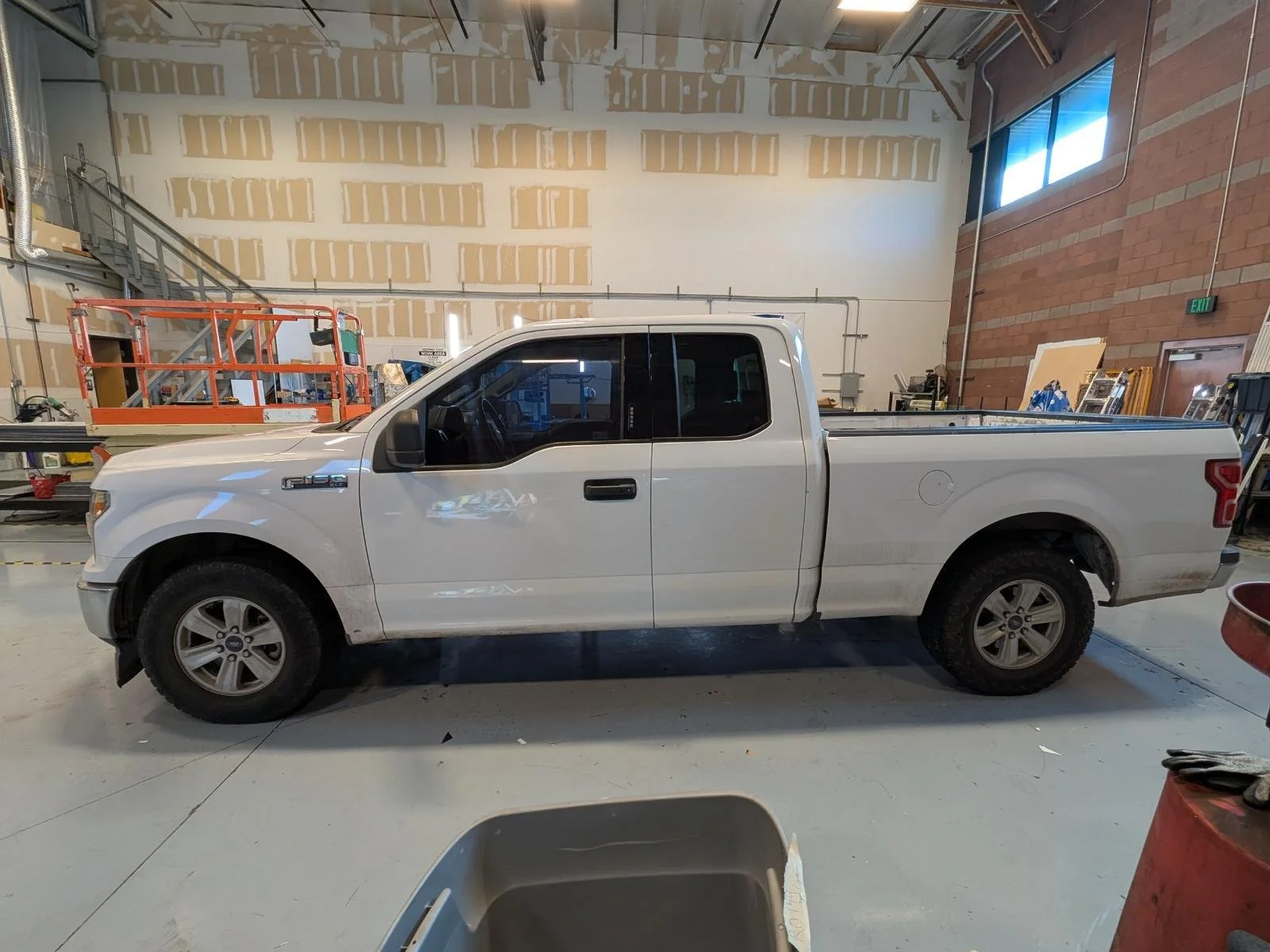 White pickup truck parked inside a warehouse with unfinished walls and equipment in the background.