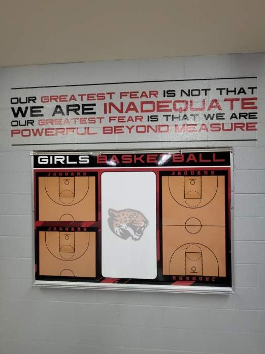 Basketball scoreboard with four court diagrams and an inspirational quote on the wall above