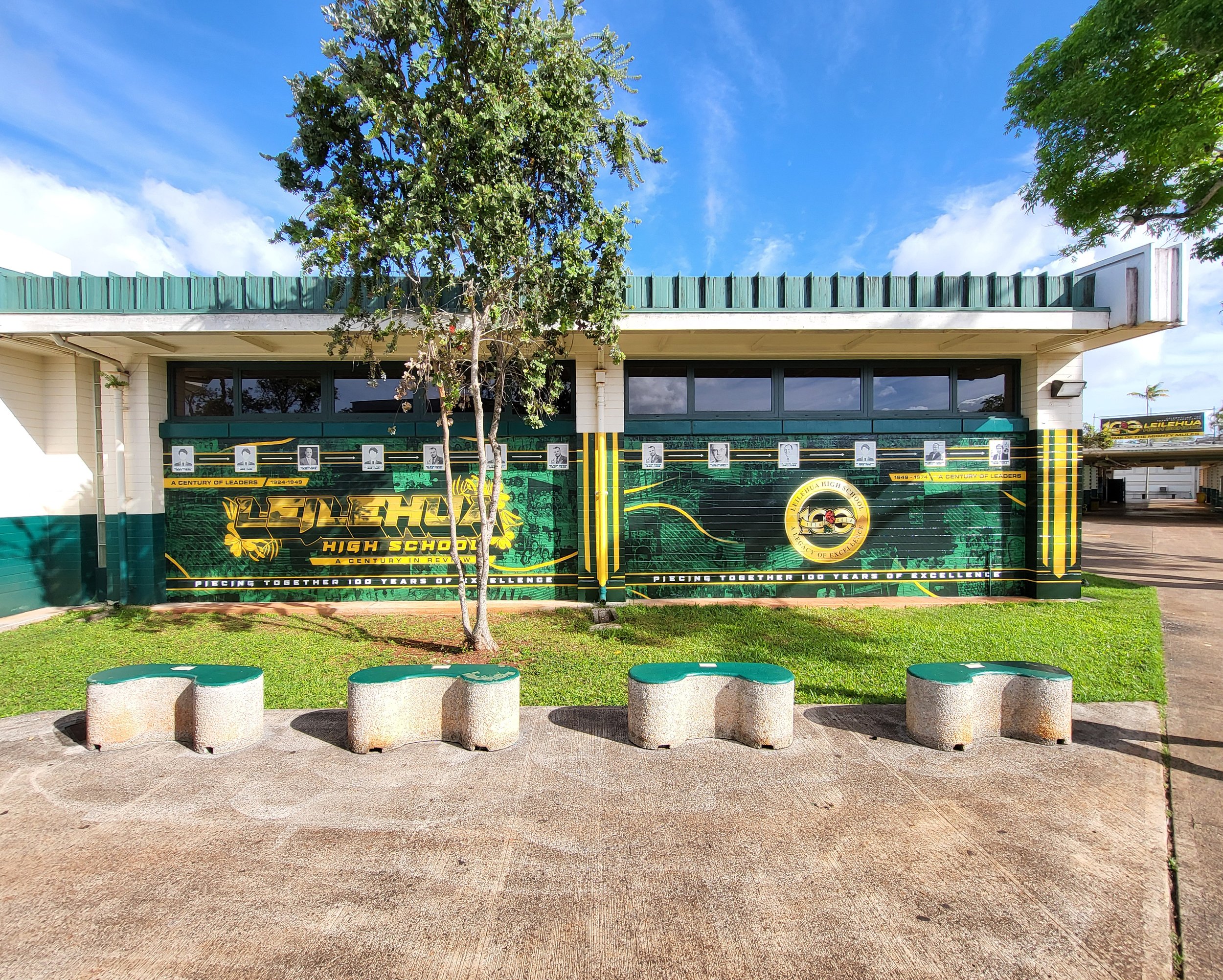 Exterior view of Leilehua High School with a green fence, trees, and blue sky in Hawaii.