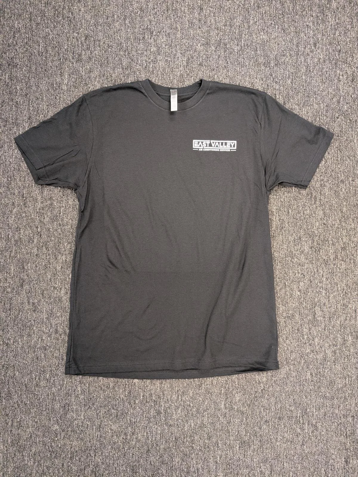 A black T-shirt with a white logo that reads 'EAST VALLEY AIR CONDITIONING SERVICES' placed on a gray carpeted floor.