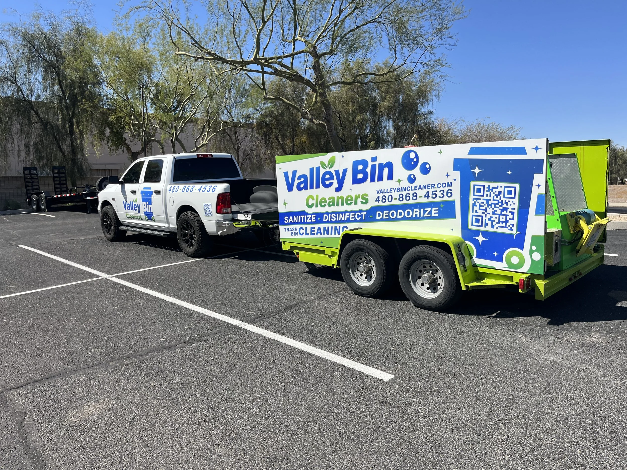 A pickup truck from Valley Bin Cleaners parked in a parking lot, with a large sign on the side advertising sanitizing, disinfecting, deodorizing, and trash bin cleaning services, along with a QR code and contact number.
