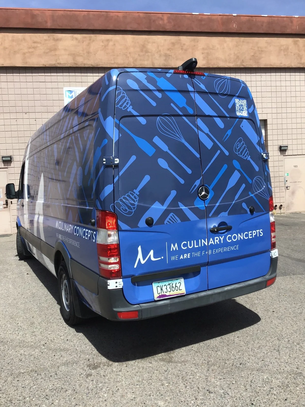 Blue Mercedes-Benz van with white and blue kitchen utensil illustrations and branding for M Culinary Concepts.