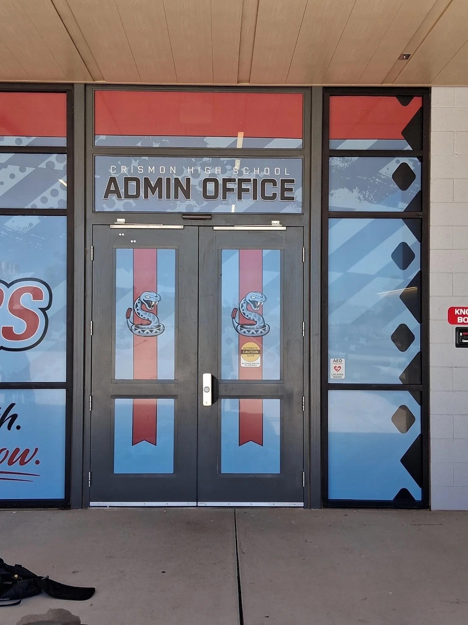 Entrance door to Crimson High School office with school mascot logos and decorative graphics.