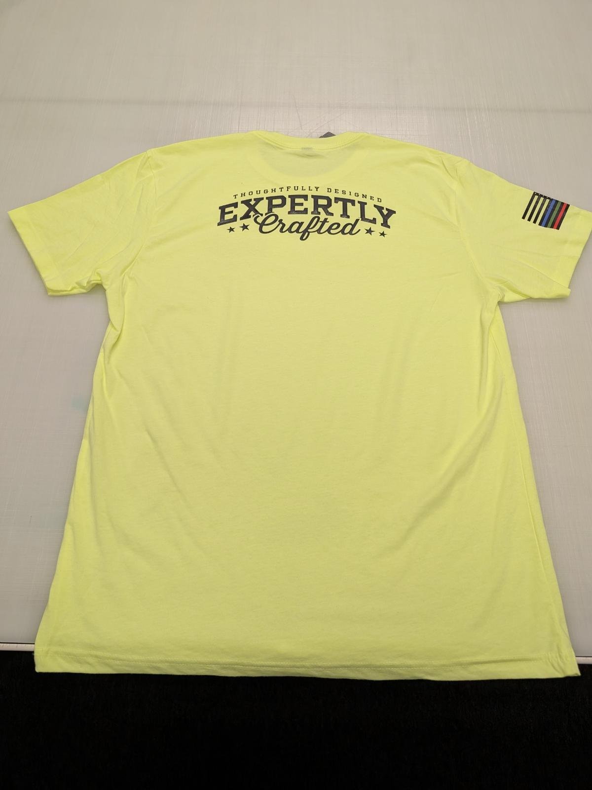 Yellow T-shirt laying flat on a surface. The back of the shirt has the text 'Thoughtfully Designed Expertly Crafted' with stars and a logo on the sleeve.
