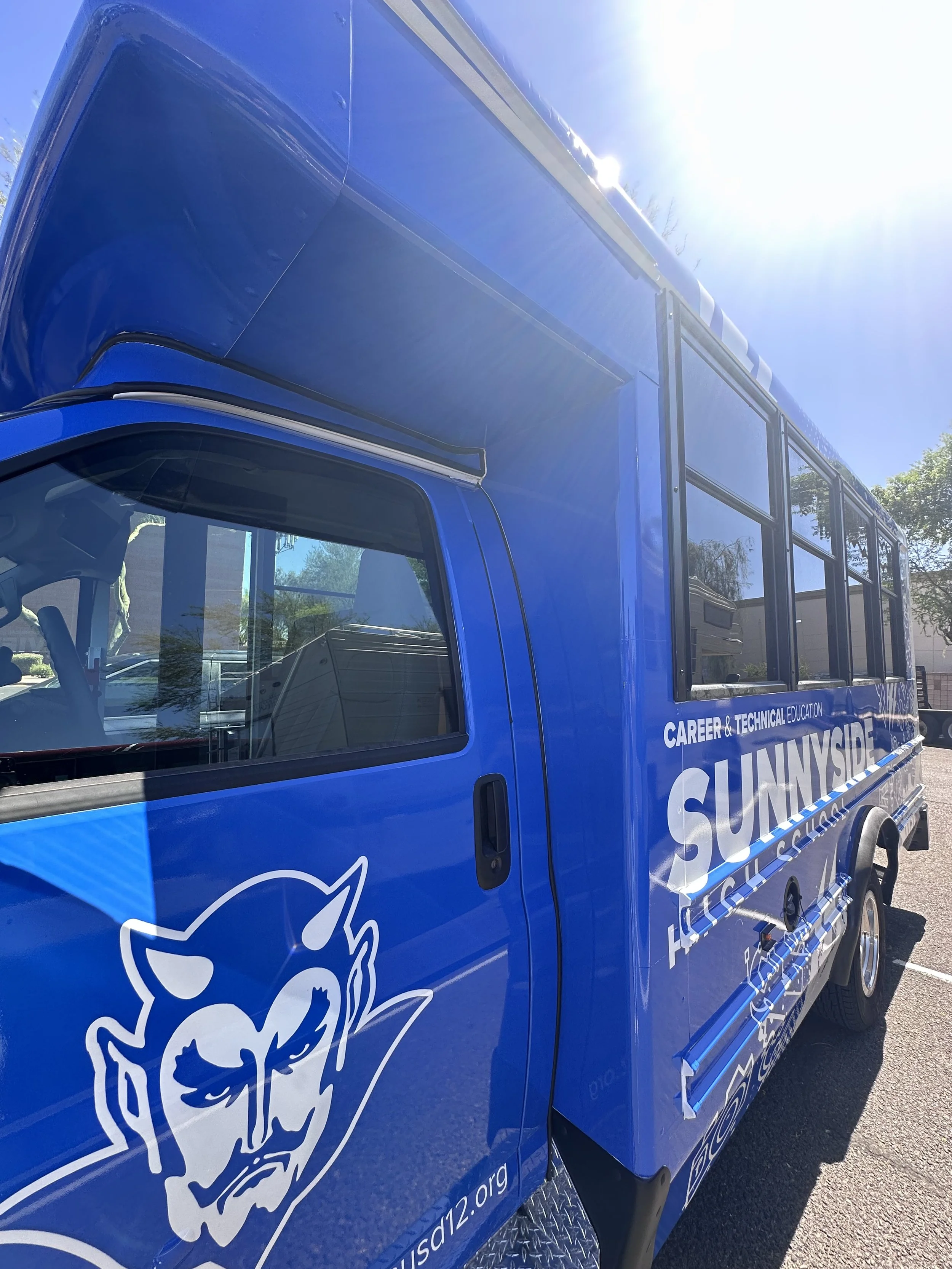 A blue vehicle with white graphics and text advertising 'Career & Technical Education' and 'SUNNYSIDE'. The vehicle also features a stylized logo of a fox's head.