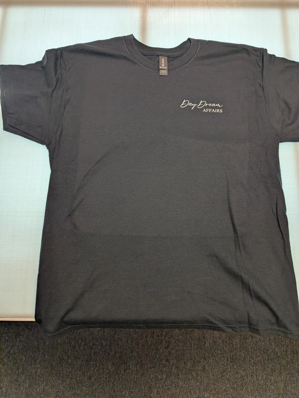 Black T-shirt with small white text on the upper left chest that reads "Day Dream AFFAIRS."