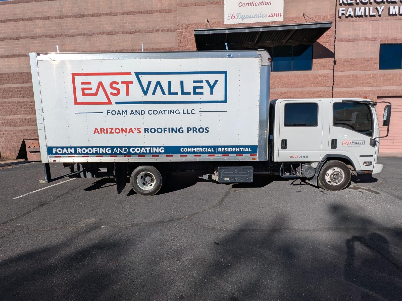 White delivery truck with East Valley Foam and Coating LLC signage parked in front of a brick building.