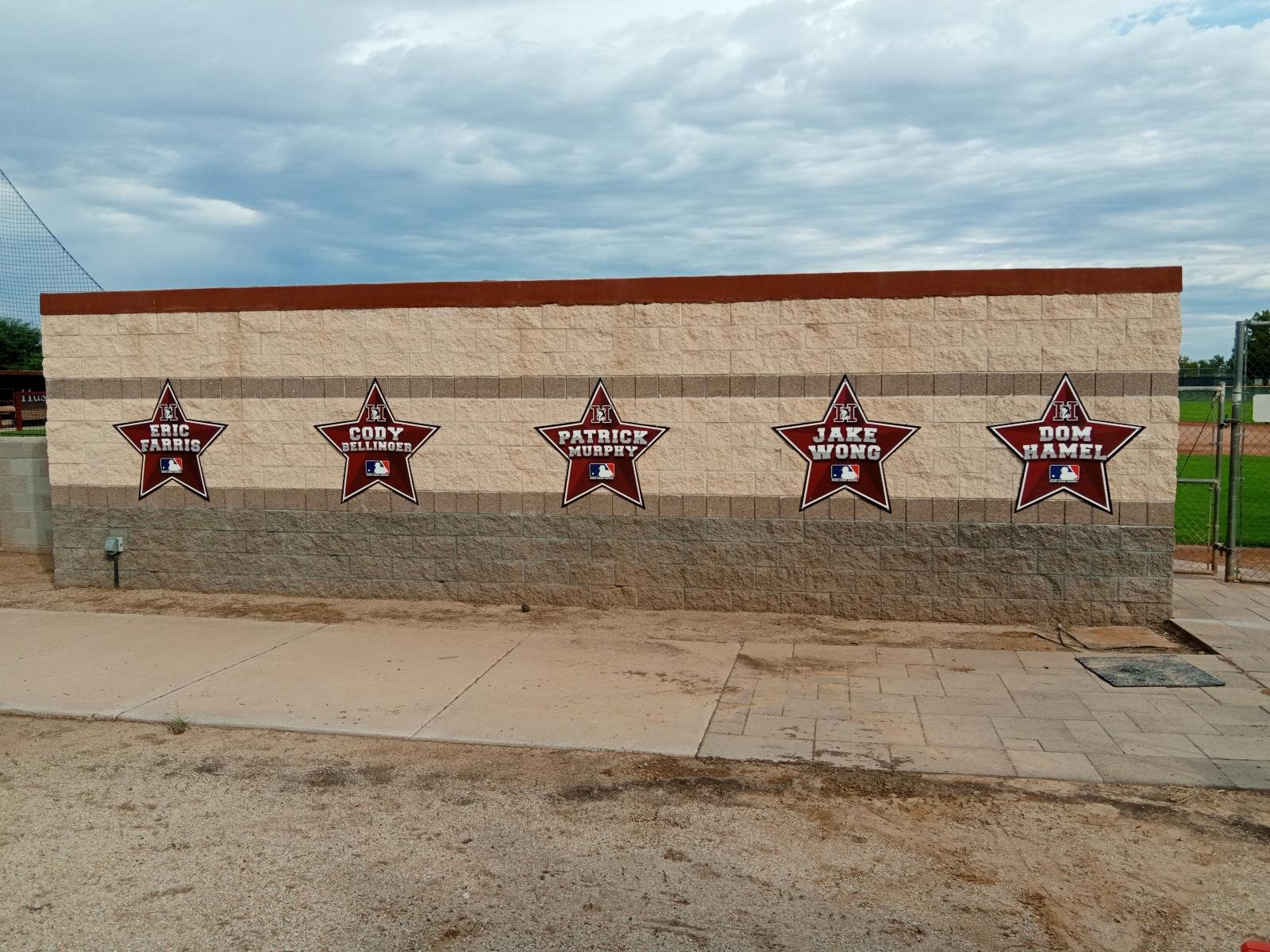 A brick wall with five red stars displaying the names of baseball players, including Eric Farris, Cody Bellinger, Patrick Murphy, Jake Wong, and Dom Hamel, with the MLB logo on each star.