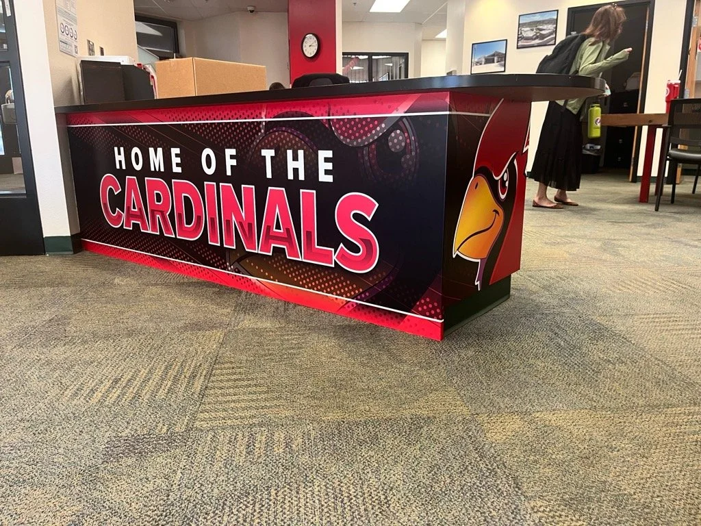 Office reception desk with a banner reading "Home of the Cardinals" and a cardinal bird logo.