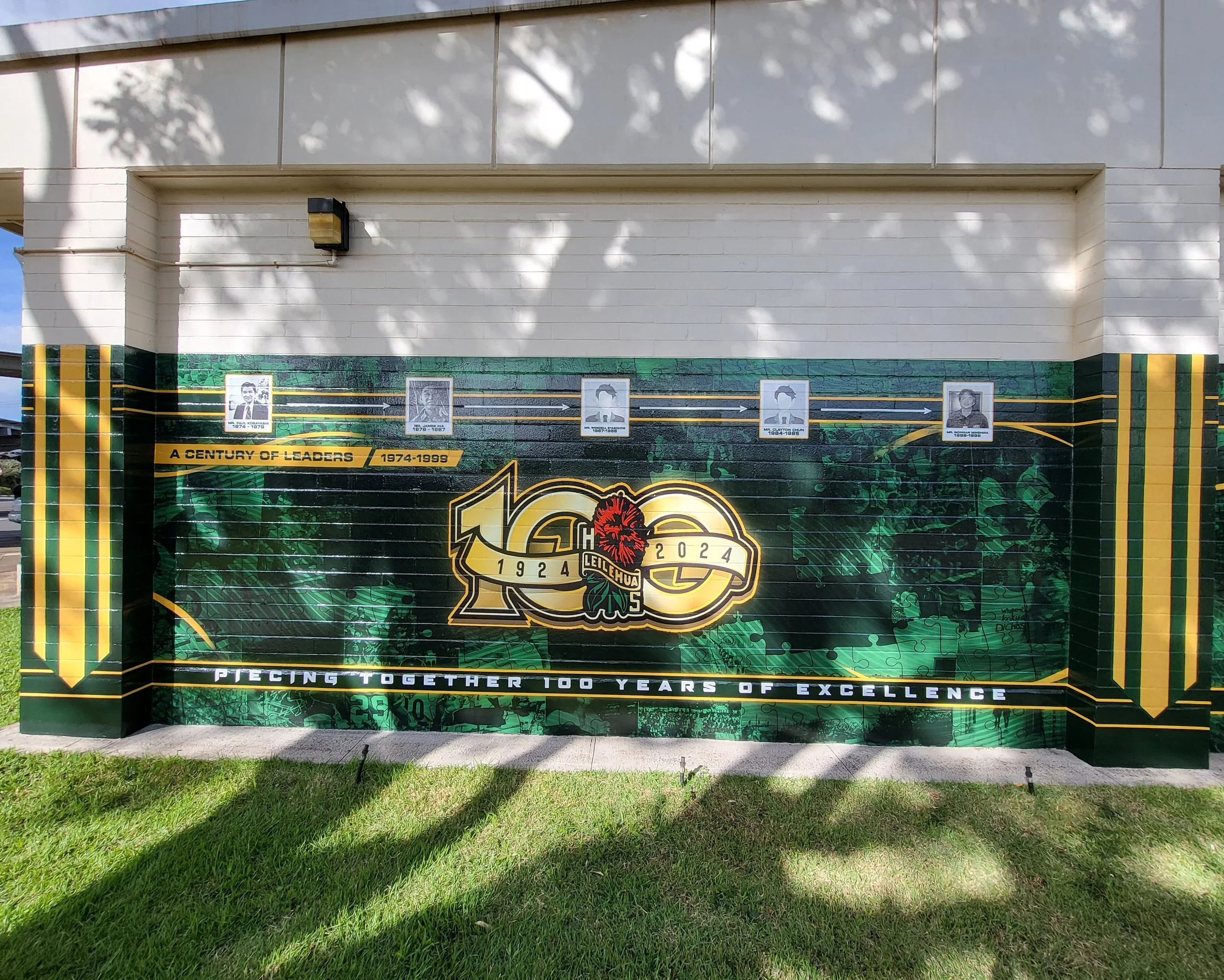 A mural celebrating 100 years of Leilehua high school from 1924 to 2024, featuring photos of past leaders and a green and black theme with a lion logo.