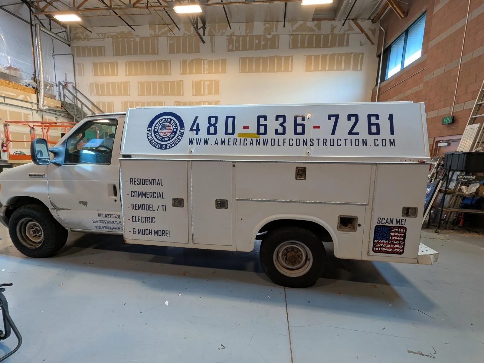 A white work truck with signage for American Wolf Construction, featuring the phone number 480-636-7261 and website www.americanwolfconstruction.com. The truck lists services including residential, commercial, remodels, electric, and more. The truck 