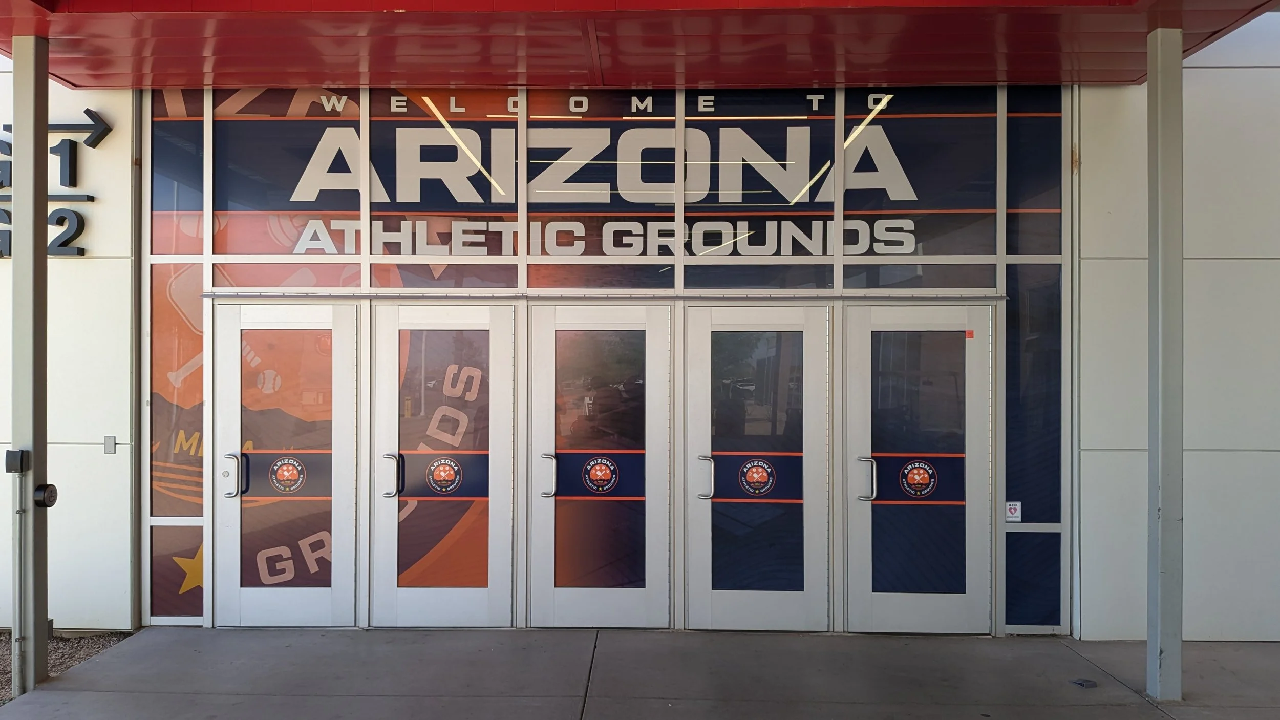 Entrance to Arizona Athletic Grounds with glass doors featuring Arizona logo decals and large window with Arizona-themed graphics.