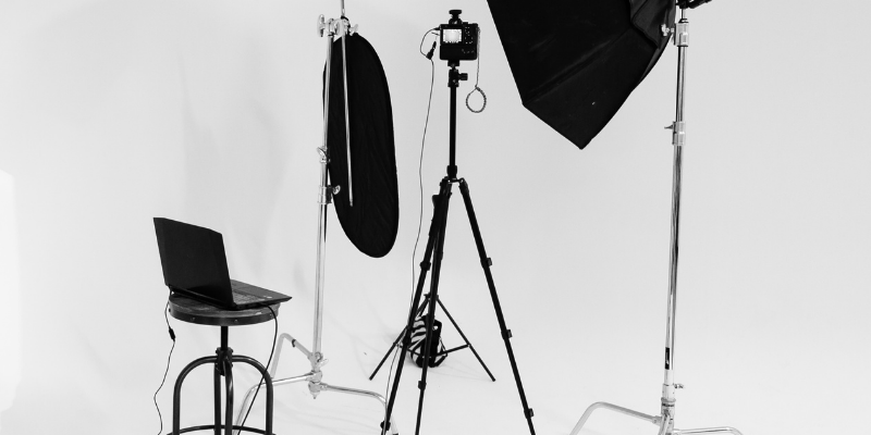 Fotostudio mit Kamera, Beleuchtung und Laptop auf weißem Hintergrund.