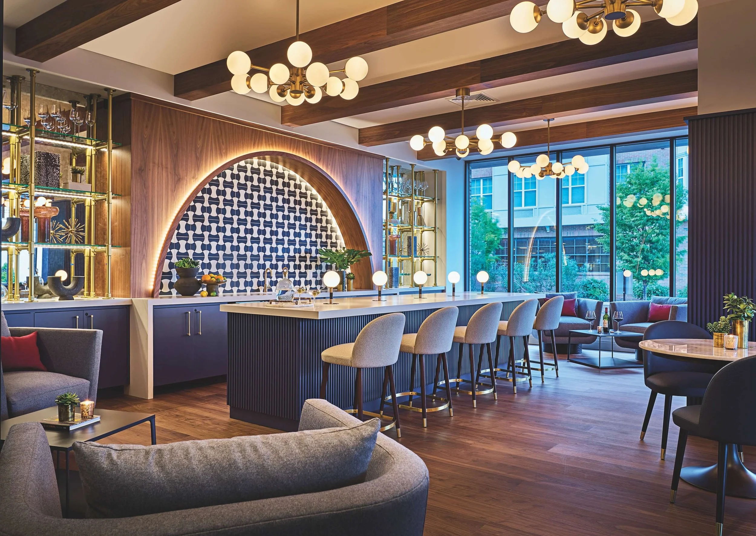 Lounge with wood accents, contemporary lighting fixtures, and large windows revealing an urban scene outside.