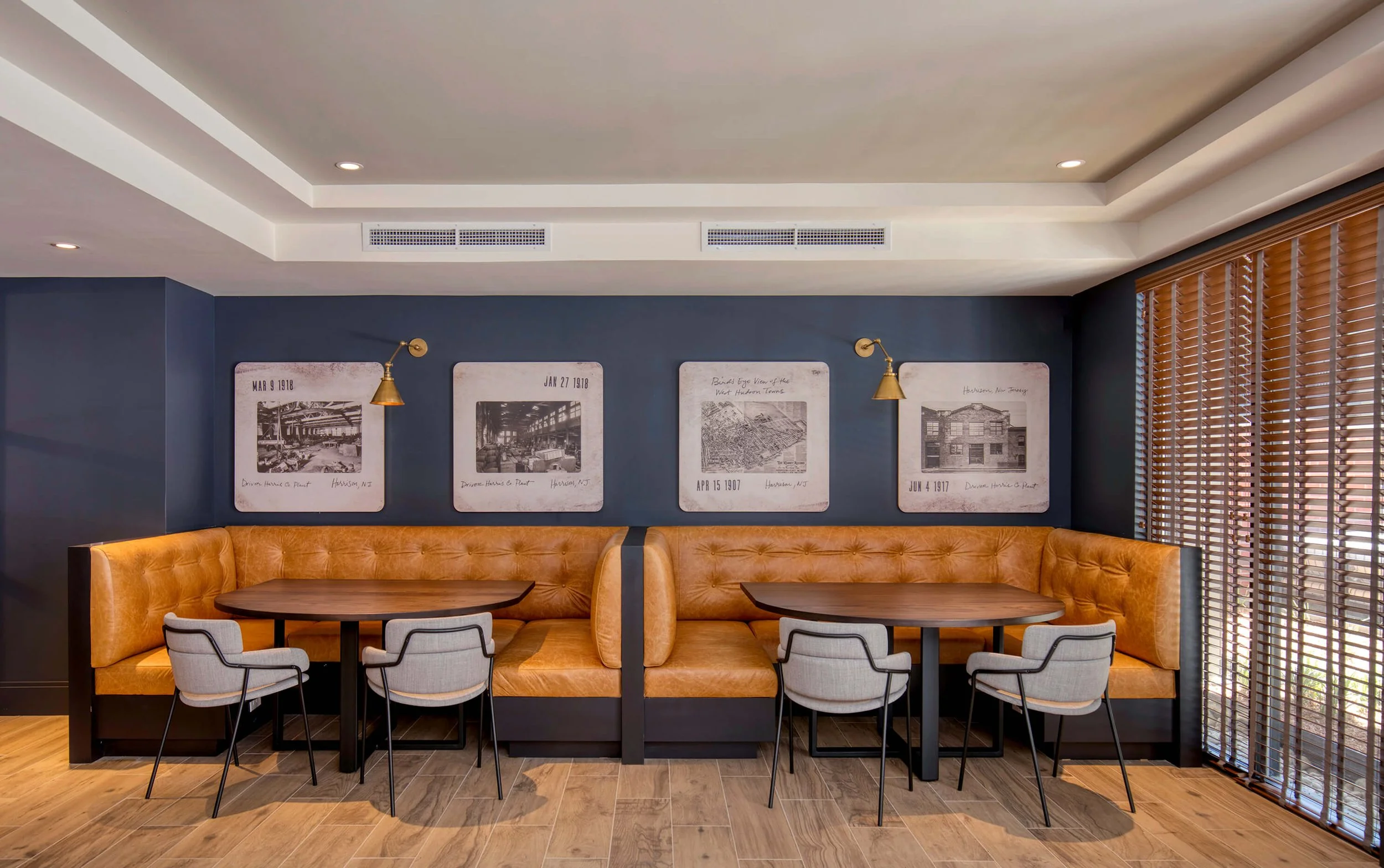 Interior of club lounge with orange cushioned booths, small tables, and gray chairs.