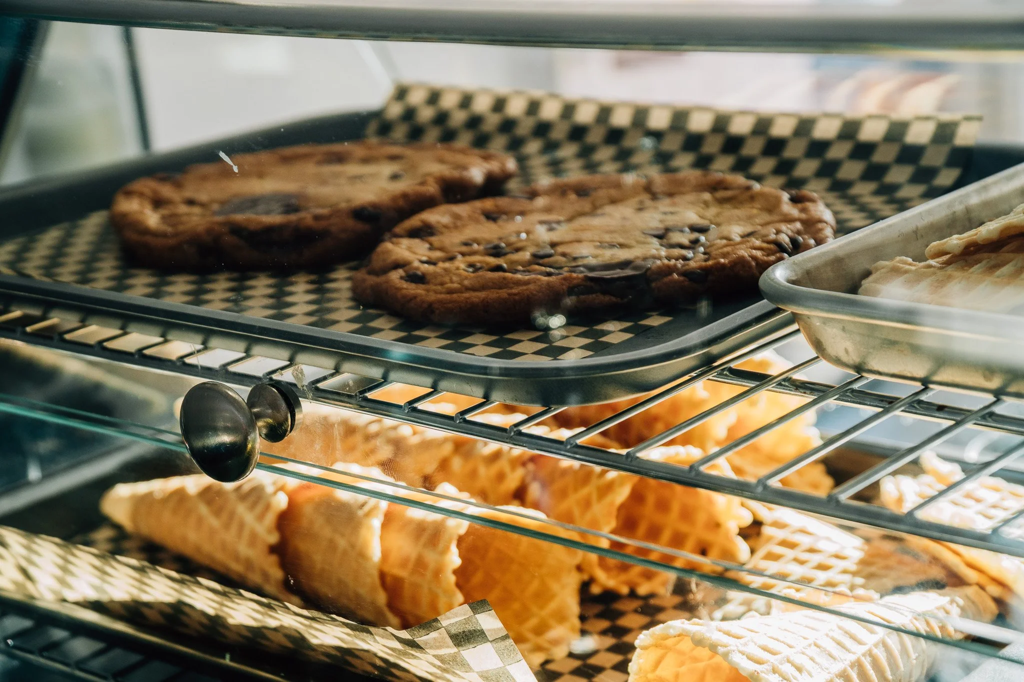 Chocolate chip cookies and pie slices inside a display case.