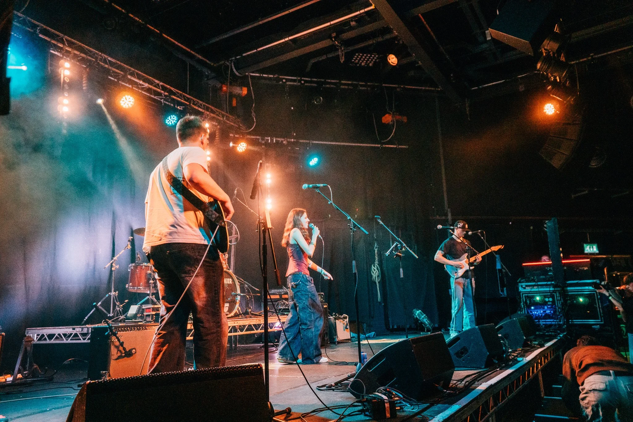 A musical band performing on stage with colorful lights and musical instruments in a concert venue.