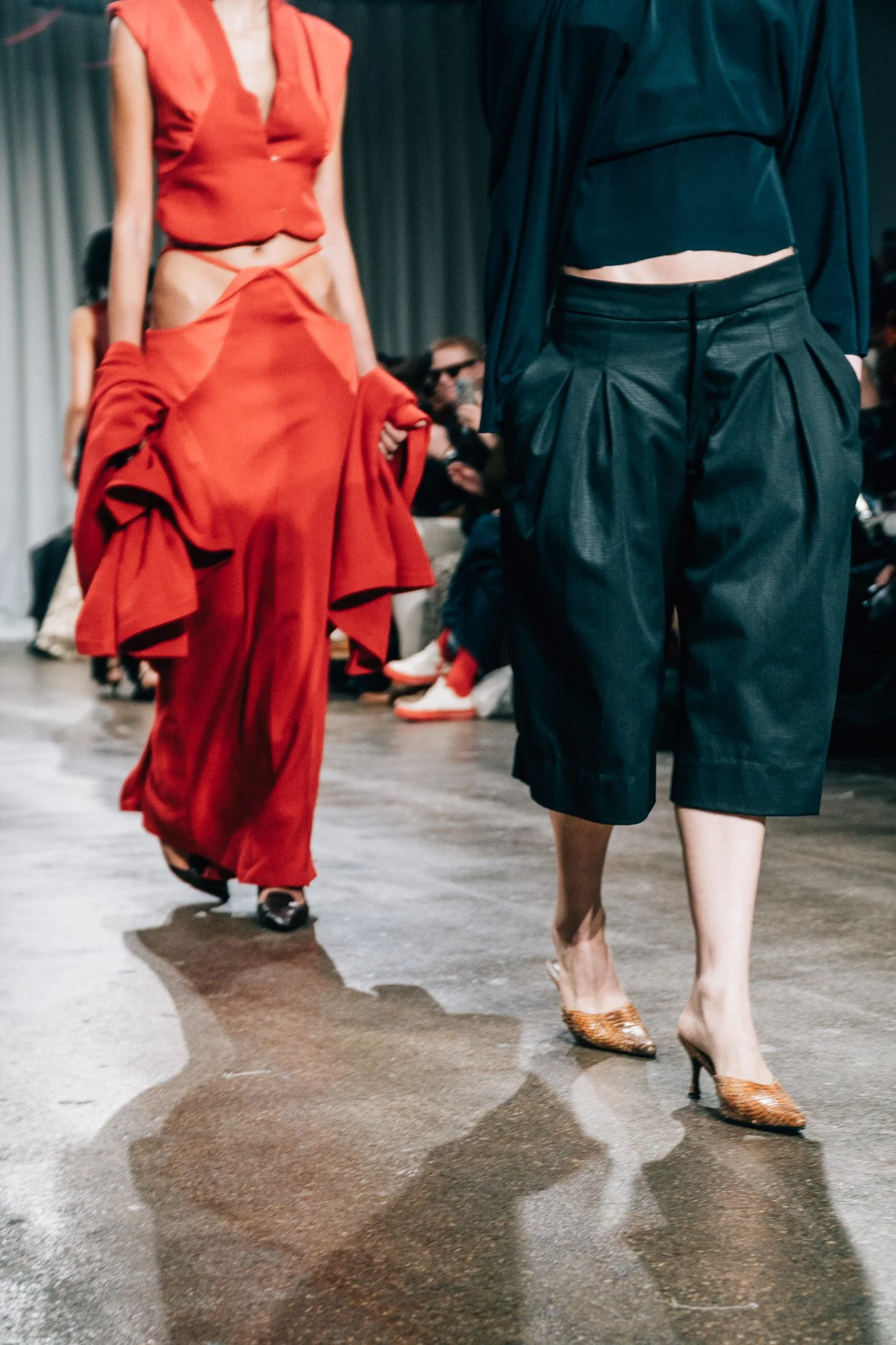 Models walking on runway during a fashion show, showcasing artistic and stylish clothing and footwear.
