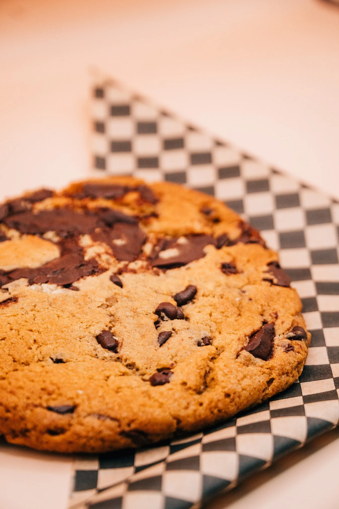 Close-up of chocolate chip cookies on checkered paper.