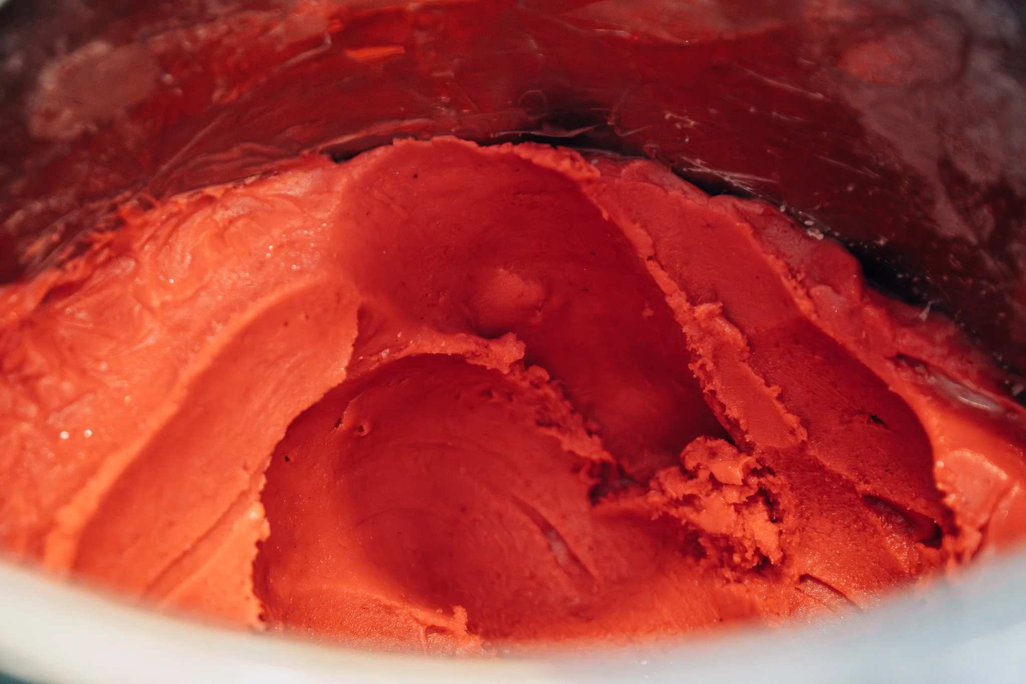 A close-up view of the inside of a container with a red, textured, dessert-like substance that appears to be a frozen or semi-frozen treat, possibly ice cream or sorbet.