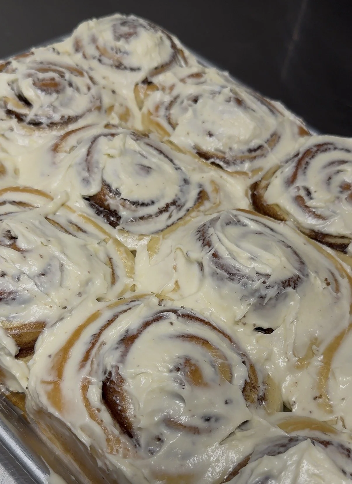 Close-up of cinnamon rolls topped with cream cheese frosting.