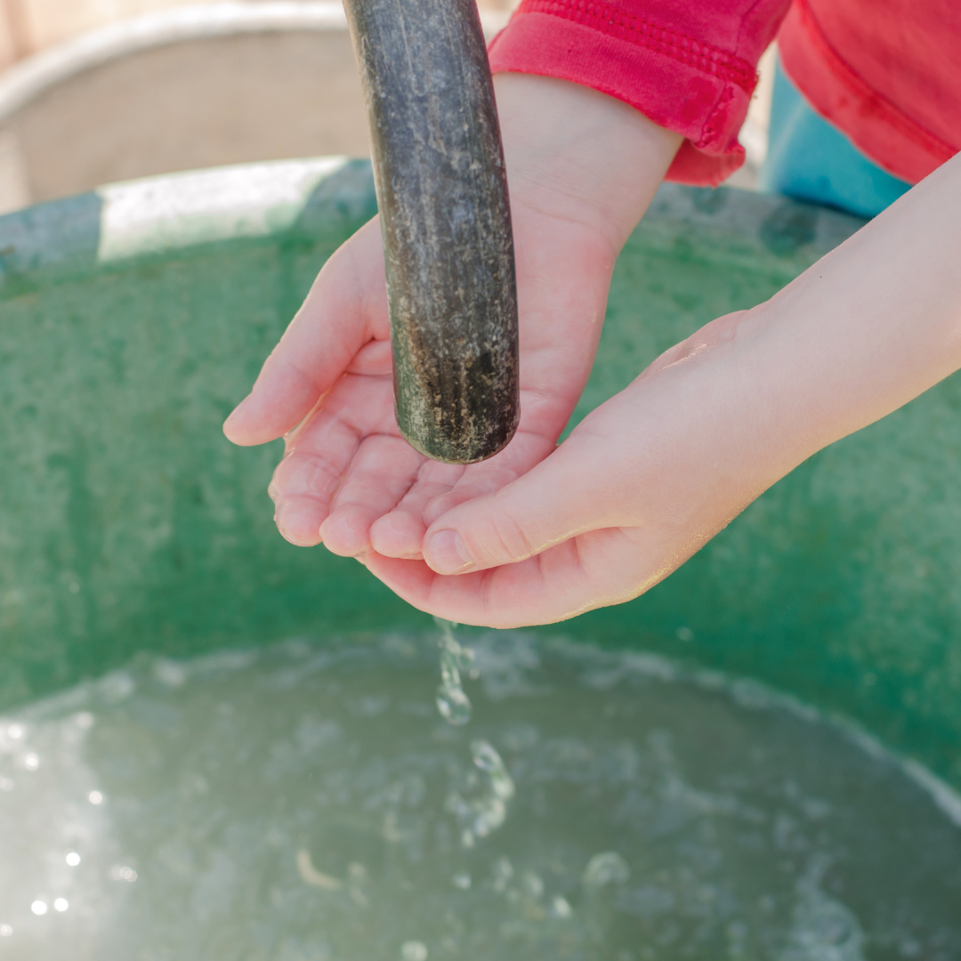 Kid with hands under running water.