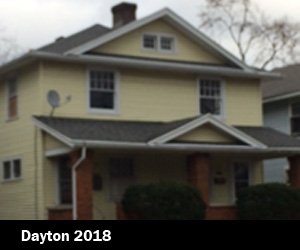 Yellow two-story house with white window frames and a front porch, located in a residential neighborhood in Dayton, 2018 depicting Good Samaritan Home's housing expansion for those looking for re-entry. 