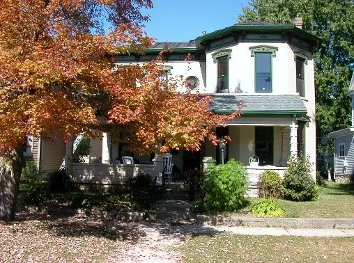 The new Good Samaritan Home white two-story house with a front porch, surrounded by trees with orange and green leaves, and lush greenery in front in Ohio.