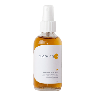 A small amber spray bottle of Sugaring LA Sunshine Skin Toner with a white label and spray nozzle