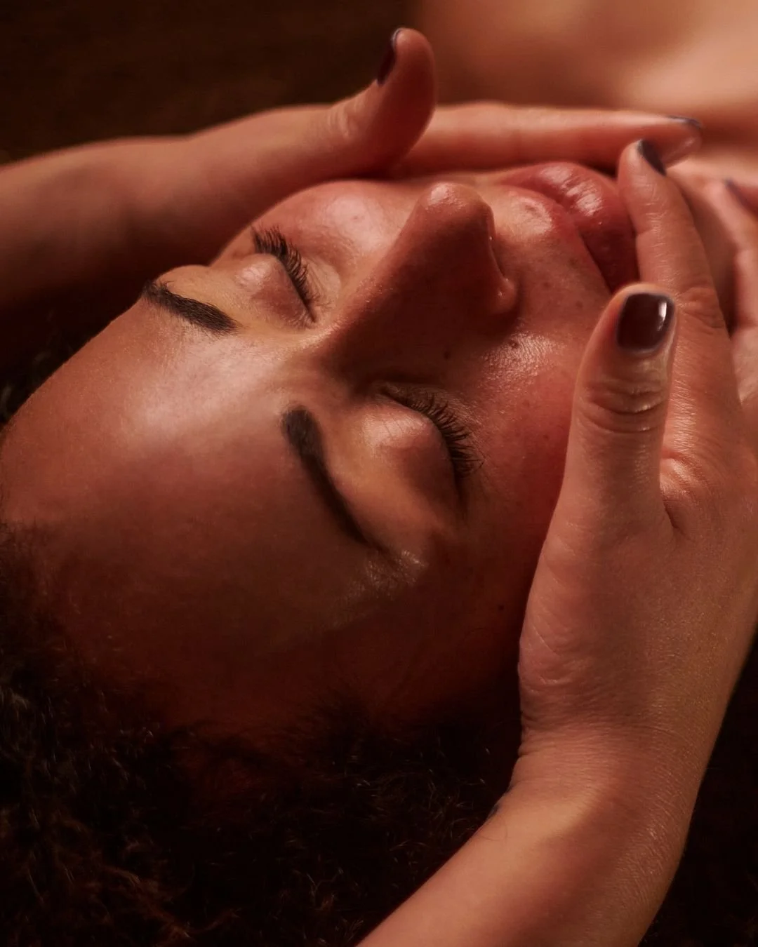 Person receiving a facial massage with closed eyes in a spa setting.