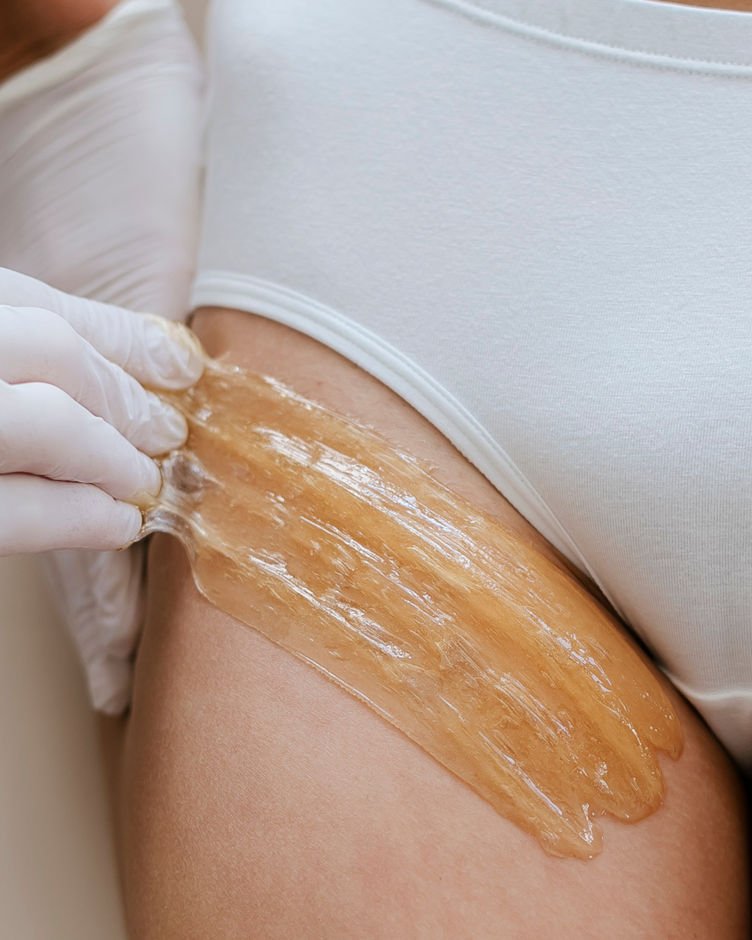 Close-up of a person waxing their thigh with a large strip of waxing paper.